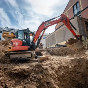 roter Kubota-Minibagger schaufelt Erde aus einer Baugrube