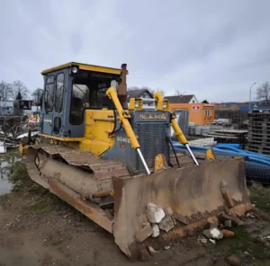 gelbe Planierraupe steht auf einer Baustelle umgeben von Baustoffen